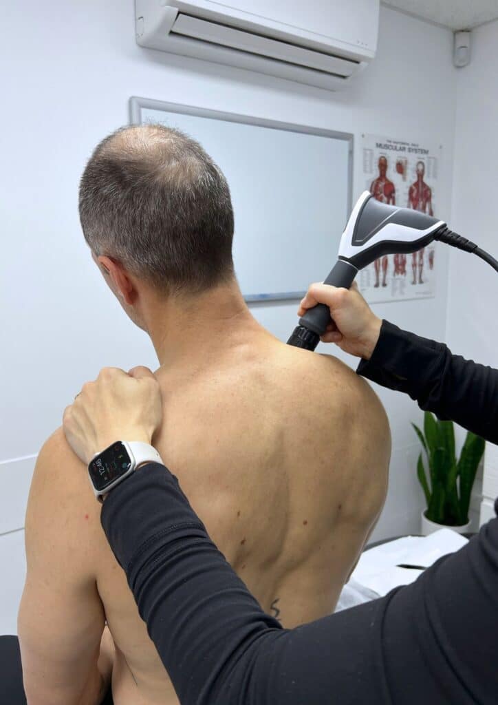 physiotherapist performing shockwave therapy in a modern clinic in West End Brisbane