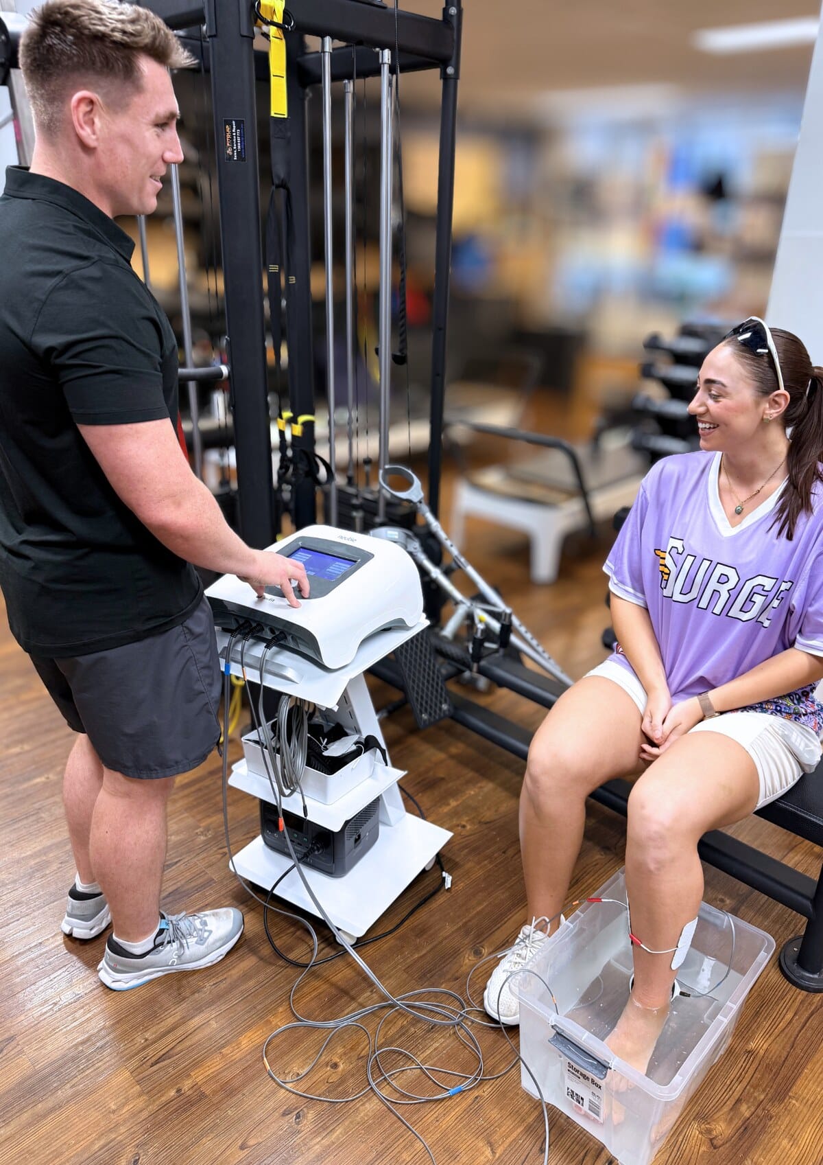 Physiotherapist adjusting Neubie stimulation settings for a patient at Forge West End, West End Brisbane